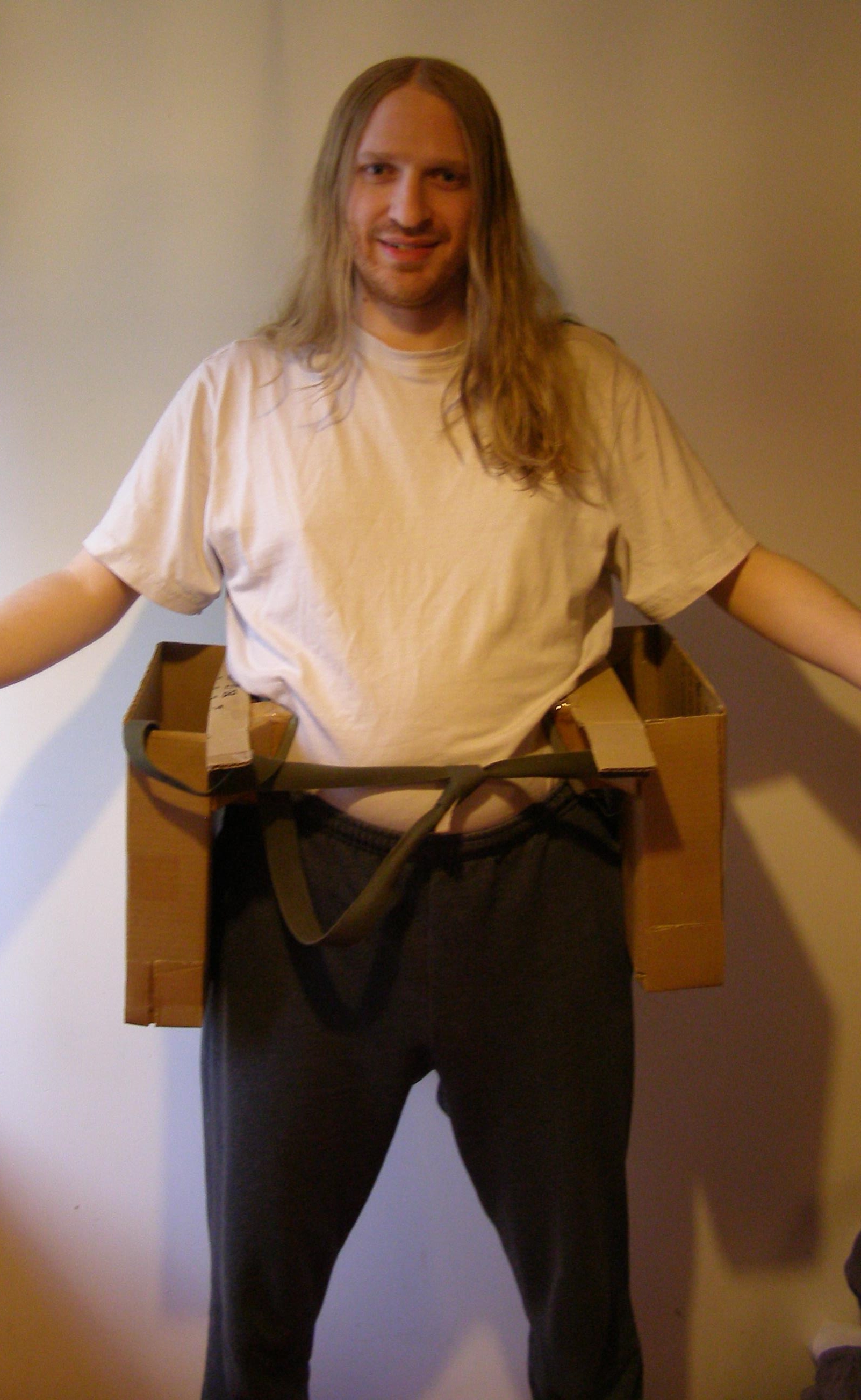 [Photo: Me, wearing Saddlebags 2.1 around my hips. They are two cardboard boxes at my sides, connected by a strap.]
