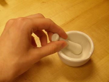 My hand holding the pestle of a mortar-and-pestle about the same width as my hand.