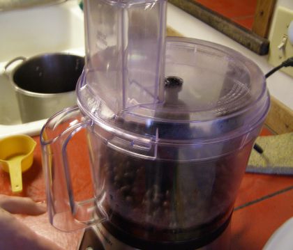 A food processor with a bunch of cooked beans in it.