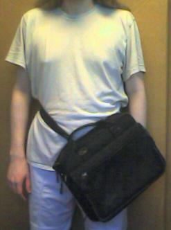 A picture of me carrying the same case, but now the strap is wrapped around my waist, so that the center of it hangs in front of my left leg.